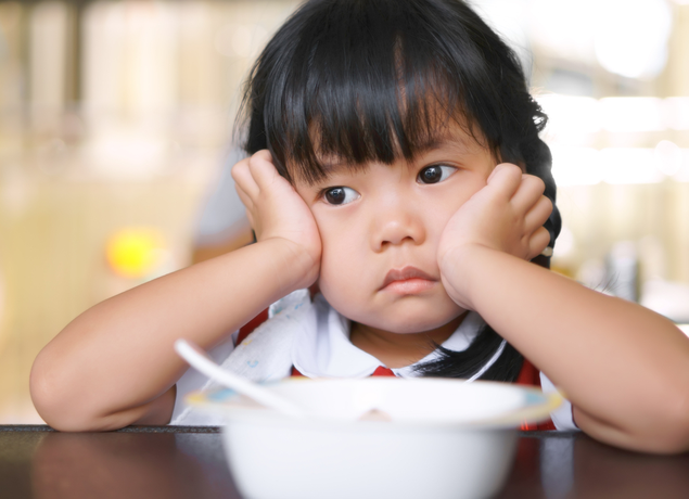 Sad girl sitting with a bowl of food