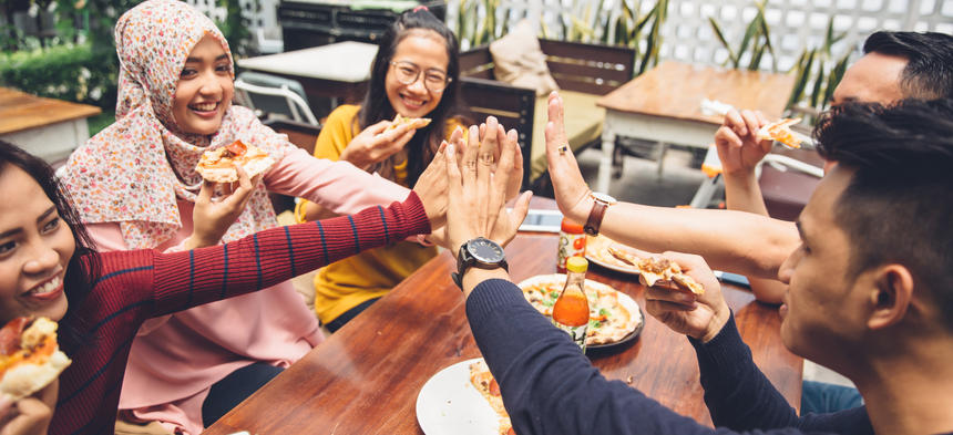 friends high fiving over a meal