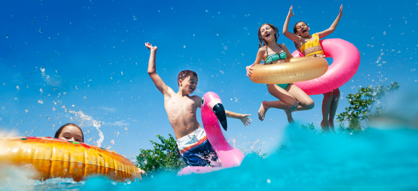 Kids splashing in a pool wearing floaties