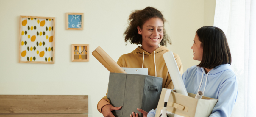 Two girls in college dorm room unpacking